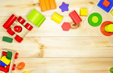 Ahşap çocuk küpleri ahşap masada. Eğitici oyuncak blokları, piramit, kalemler, numaralar. Anaokulu, anaokulu ya da kreş için oyuncaklar. Uzayı metin için kopyala. Üst görünüm