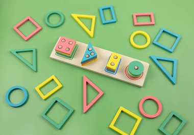 Yeşil arka planda çok renkli ahşap bloklar. Moda bulmaca oyuncakları. Geometrik şekiller: kare, daire, üçgen, dikdörtgen. Anaokulu, anaokulu ya da kreş için eğitici oyuncaklar. Okula geri dön.