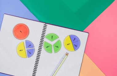 Açık not defterinde çok renkli matematik kesirleri var. Çocuklar için ilginç matematik, geometri şekilleri. Eğitim, okula dönüş konsepti.