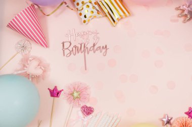 Doğum günü kutlaması ya da parti için arka plan. Renkli balonlar, konfetiler, mumlar, pastel pembe arka planda kurdeleler. Kopyalama alanı olan bir model, metin için bir yer
