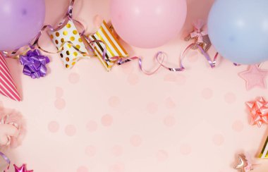 Doğum günü kutlaması ya da parti için arka plan. Renkli balonlar, konfetiler, mumlar, pastel pembe arka planda kurdeleler. Kopyalama alanı olan bir model, metin için bir yer