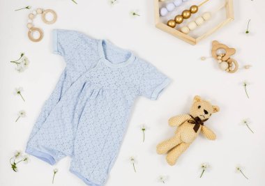 Beyaz masada yeni doğmuş bir çocuk için mavi beden, ayı ve aksesuarlar. Çevre dostu tahta oyuncaklarla organik pamuktan bebek bedeni modeli. Bebek partisi, festival, doğum günü süsü. Üst görünüm