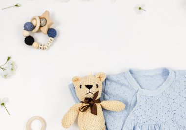 Beyaz masada yeni doğmuş bir çocuk için mavi beden, ayı ve aksesuarlar. Çevre dostu tahta oyuncaklarla organik pamuktan bebek bedeni modeli. Bebek partisi, festival, doğum günü süsü. Üst görünüm