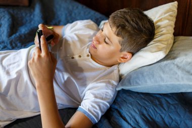 Kırık eli olan tatlı çocuk dinleniyor. Kapatın genç yakışıklı. Sarı alçılı genç evde akıllı telefon oynuyor..