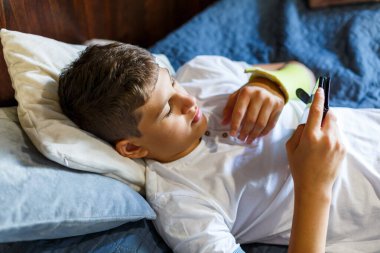 Kırık eli olan tatlı çocuk dinleniyor. Kapatın genç yakışıklı. Sarı alçılı genç evde akıllı telefon oynuyor..