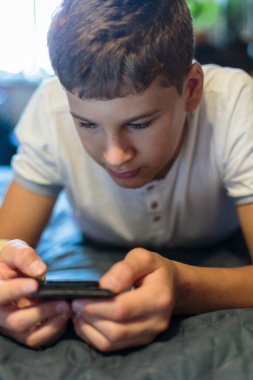 Kırık eli olan tatlı çocuk dinleniyor. Kapatın genç yakışıklı. Sarı alçılı genç evde akıllı telefon oynuyor..