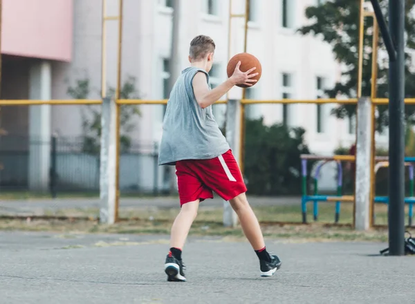 티셔츠를 귀여운 놀이터에서 농구를 합니다 활동적 청소년 오렌지 가지고 경기를 — 스톡 사진