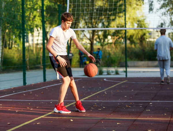 티셔츠를 귀여운 운동장에서 농구를 합니다 활동적 청소년 오렌지 가지고 경기를 — 스톡 사진
