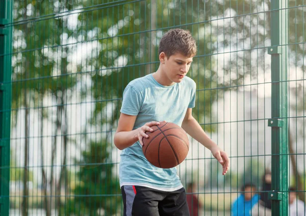 티셔츠를 귀여운 놀이터에서 농구를 합니다 활동적 청소년 오렌지 가지고 경기를 — 스톡 사진