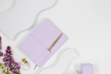 Beyaz arka planda mor planlayıcı, çiçekler ve geometrik şekiller. Üst manzara, düz yatış. Moda kadın aksesuarları..