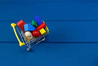 Çok renkli ahşap bloklar, arabalar, mavi arka planda bir sepetin içinde tren. Moda çevre dostu yapboz oyuncakları. Anaokulu ve anaokulu için eğitici oyuncaklar. Okula dönelim. Okul için online alışveriş.