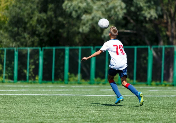 青いスポーツウェアを着た若いスポーツ少年たちが走り ピッチ上でボールを蹴ります サッカーユースチームは夏にサッカーをする 子供のための活動 トレーニング — ストック写真