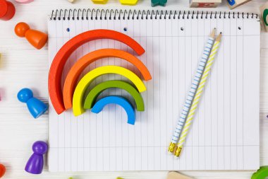 Not defterini, kalemleri, beyaz ahşap bir masada çok renkli blokları aç. Okula dönmek, eğitim kavramı.