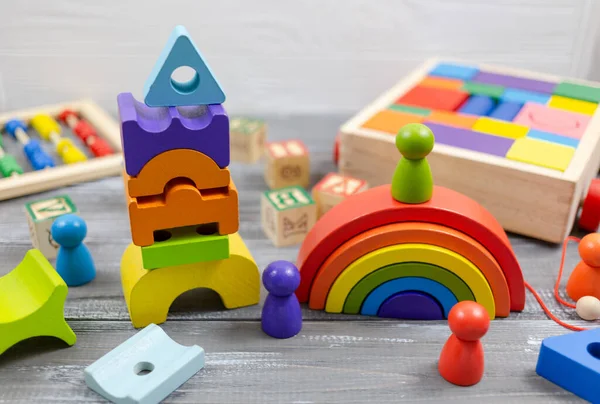 Wooden multicolored toy house, pyramid, blocks on wooden table. Back to school, games for kindergarten, preschool education.