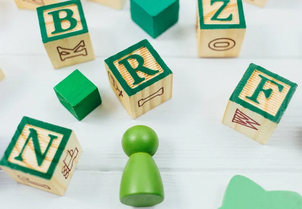 Green wooden alphabet blocks on a white wooden table. Back to school, games for kindergarten, preschool education.