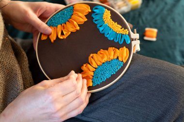 Rahatlatıcı bir öğleden sonra, renkli iplikler ve kumaşlarla dolu koyu bir arka planda canlı çiçeklerin yer aldığı yaratıcı nakış projesi