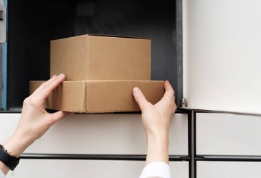 Eller, karton bir kutuyu teslimat yerine koyar. Gündüz civarı, modern bir bölgede.