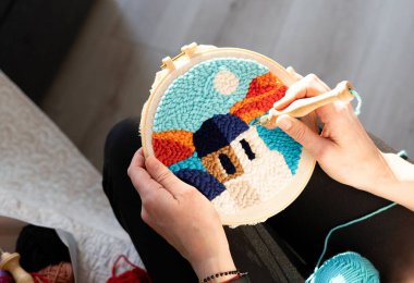 Eller renkli bir nakış üzerinde çalışıyor. İyi aydınlatılmış bir odada kancayla.