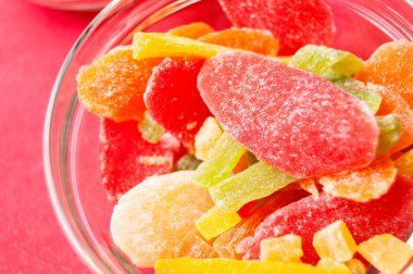 çok renkli bir cam kase kırmızı bir arka plan üzerinde kurutulmuş ananas parçaları