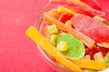 çok renkli bir cam kase kırmızı bir arka plan üzerinde kurutulmuş ananas parçaları