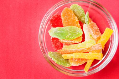 çok renkli bir cam kase kırmızı bir arka plan üzerinde kurutulmuş ananas parçaları