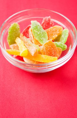 çok renkli bir cam kase kırmızı bir arka plan üzerinde kurutulmuş ananas parçaları