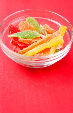 çok renkli bir cam kase kırmızı bir arka plan üzerinde kurutulmuş ananas parçaları