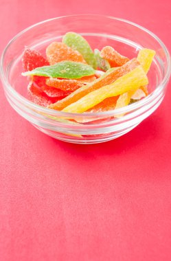 çok renkli bir cam kase kırmızı bir arka plan üzerinde kurutulmuş ananas parçaları