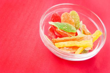 çok renkli bir cam kase kırmızı bir arka plan üzerinde kurutulmuş ananas parçaları