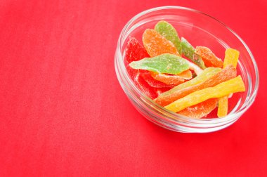 çok renkli bir cam kase kırmızı bir arka plan üzerinde kurutulmuş ananas parçaları