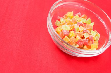 çok renkli bir cam kase kırmızı bir arka plan üzerinde kurutulmuş ananas parçaları