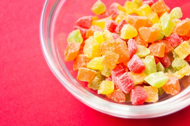 çok renkli bir cam kase kırmızı bir arka plan üzerinde kurutulmuş ananas parçaları