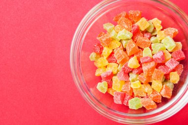 çok renkli bir cam kase kırmızı bir arka plan üzerinde kurutulmuş ananas parçaları