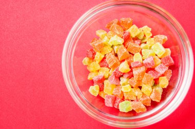 çok renkli bir cam kase kırmızı bir arka plan üzerinde kurutulmuş ananas parçaları