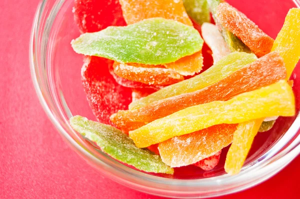 çok renkli bir cam kase kırmızı bir arka plan üzerinde kurutulmuş ananas parçaları