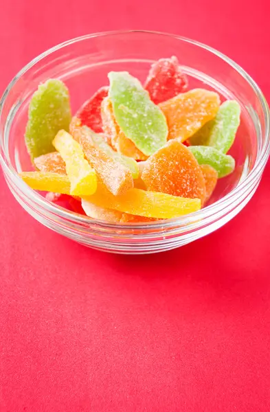 çok renkli bir cam kase kırmızı bir arka plan üzerinde kurutulmuş ananas parçaları