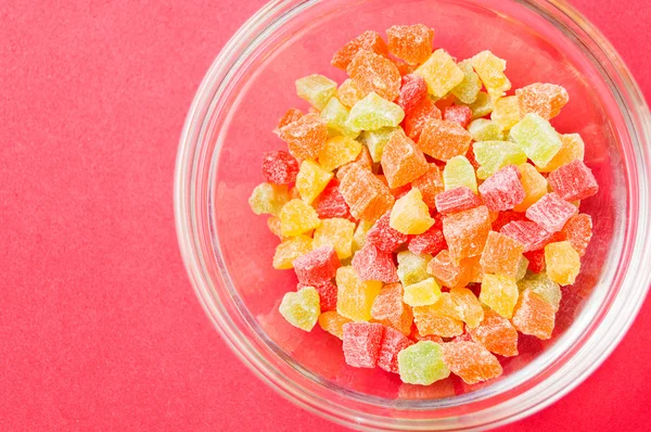 çok renkli bir cam kase kırmızı bir arka plan üzerinde kurutulmuş ananas parçaları