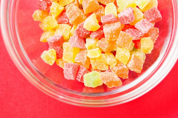 çok renkli bir cam kase kırmızı bir arka plan üzerinde kurutulmuş ananas parçaları