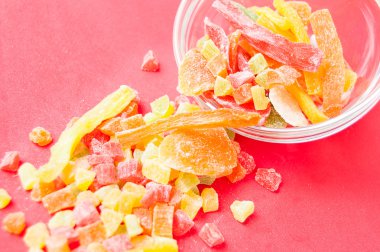 çok renkli bir cam kabın içinde ve yakın kase kırmızı bir arka plan üzerinde kurutulmuş ananas parçaları