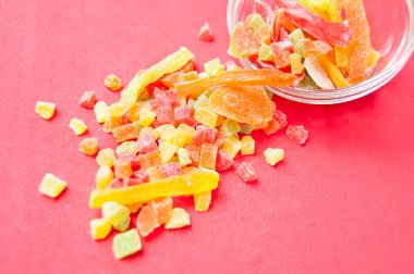 çok renkli bir cam kabın içinde ve yakın kase kırmızı bir arka plan üzerinde kurutulmuş ananas parçaları