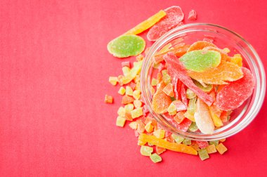 çok renkli bir cam kabın içinde ve yakın kase kırmızı bir arka plan üzerinde kurutulmuş ananas parçaları