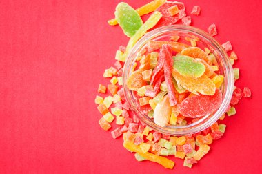 çok renkli bir cam kabın içinde ve yakın kase kırmızı bir arka plan üzerinde kurutulmuş ananas parçaları