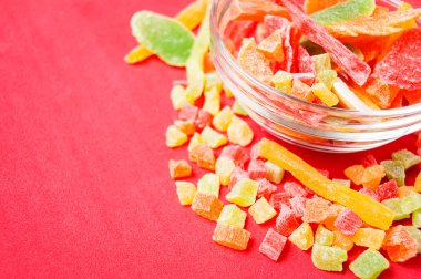 çok renkli bir cam kabın içinde ve yakın kase kırmızı bir arka plan üzerinde kurutulmuş ananas parçaları