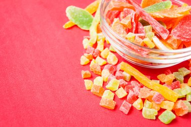 çok renkli bir cam kabın içinde ve yakın kase kırmızı bir arka plan üzerinde kurutulmuş ananas parçaları