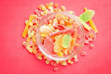 çok renkli bir cam kabın içinde ve yakın kase kırmızı bir arka plan üzerinde kurutulmuş ananas parçaları