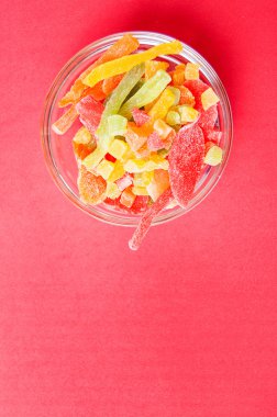 çok renkli bir cam kase kırmızı bir arka plan üzerinde kurutulmuş ananas parçaları