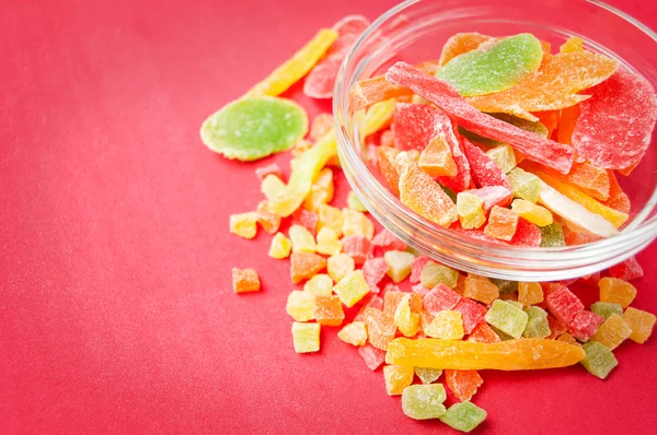 çok renkli bir cam kabın içinde ve yakın kase kırmızı bir arka plan üzerinde kurutulmuş ananas parçaları