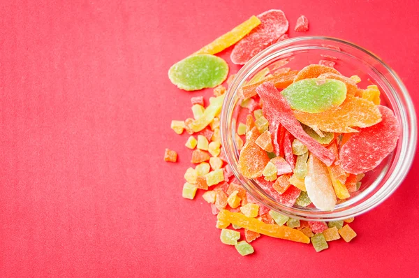 çok renkli bir cam kabın içinde ve yakın kase kırmızı bir arka plan üzerinde kurutulmuş ananas parçaları