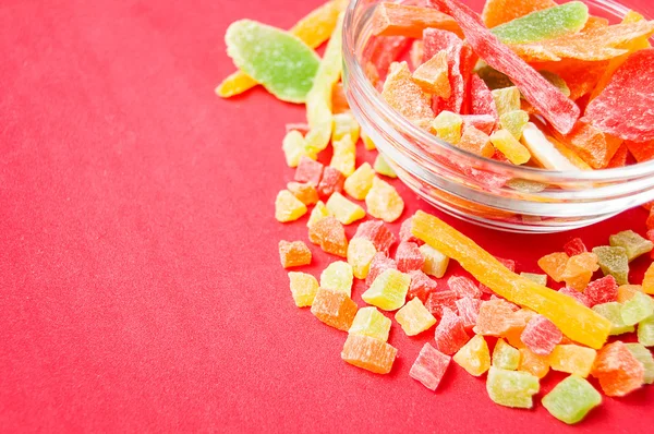 çok renkli bir cam kabın içinde ve yakın kase kırmızı bir arka plan üzerinde kurutulmuş ananas parçaları