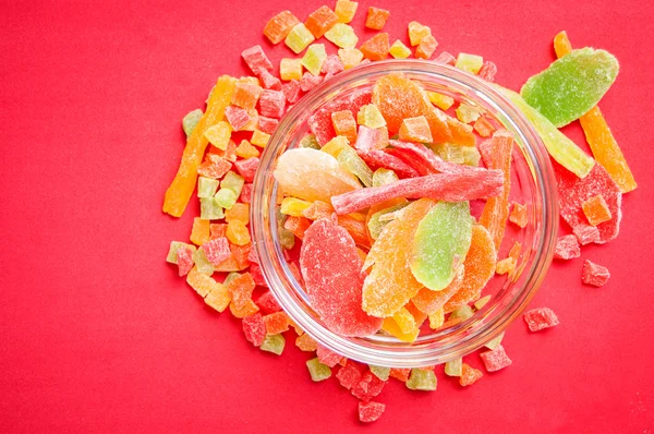 çok renkli bir cam kabın içinde ve yakın kase kırmızı bir arka plan üzerinde kurutulmuş ananas parçaları